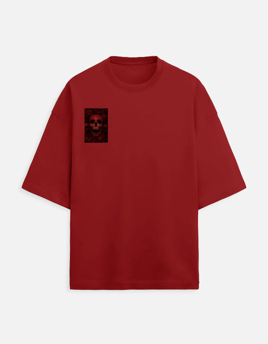 Color_Red. A minimalist, deep red oversized crewneck T-shirt featuring a small, rectangular graphic of a skull on the left chest. The shirt has a boxy, modern fit with wide half-sleeves and a clean, seamless finish.