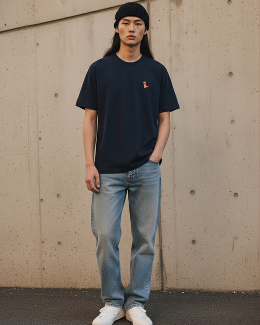 Oversized deep navy streetwear t-shirt with a small orange dinosaur embroidery on the chest. Features dropped shoulders, heavyweight cotton fabric, and a boxy fit.
