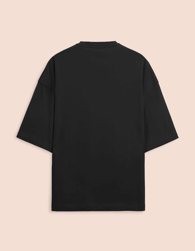 Black oversized unisex t-shirt featuring a centered, small graphic of the text "Nirogi Aatma" (Healthy Soul) written in bold red lettering. Soft cotton, drop-shoulder, boxy casual apparel with a spiritual or motivational typographic design.