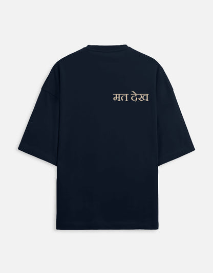 Navy Blue oversized unisex t-shirt with a dual-sided graphic. The front features the Hindi text "Dekh Lunga" (I will handle it) in light gray. The back features the Hindi text "मत देख" (Mat Dekh - Don't look) in light gold, positioned on the upper center. Boxy fit, typographic statement apparel.