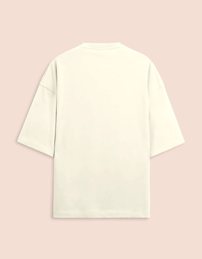 Cream or off-white oversized unisex t-shirt featuring a centered, small graphic of the text "Nirogi Aatma" (Healthy Soul) written in bold red lettering. Soft cotton, drop-shoulder, boxy casual apparel with a spiritual or motivational typographic design.