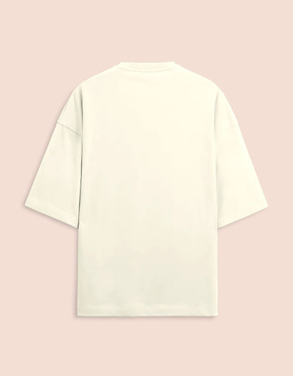 Cream or off-white oversized unisex t-shirt featuring a centered, small graphic of the text "Nirogi Aatma" (Healthy Soul) written in bold red lettering. Soft cotton, drop-shoulder, boxy casual apparel with a spiritual or motivational typographic design.