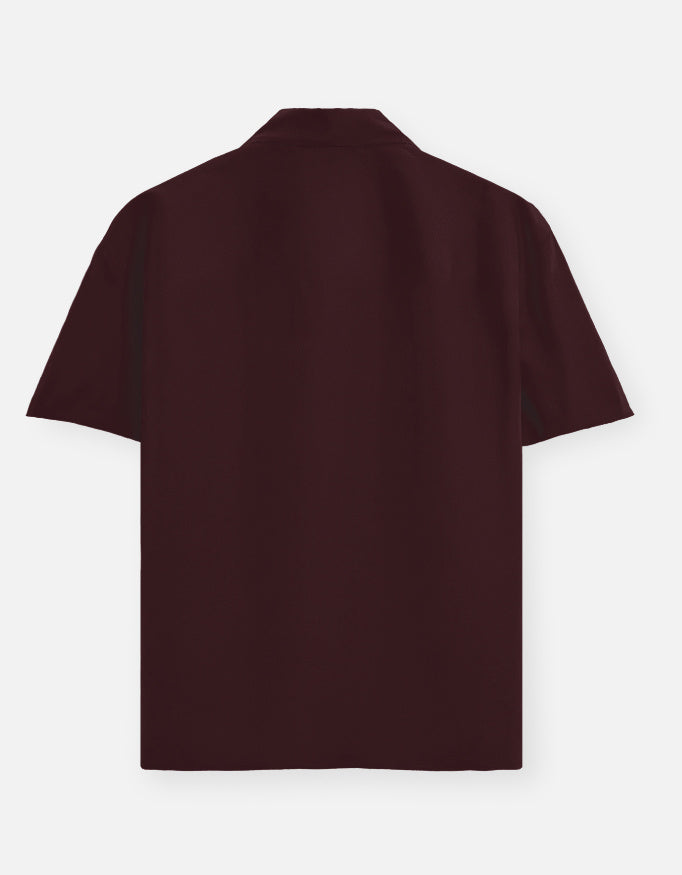 Color_Maroon. Premium unisex oversized button-down shirt with a wide, boxy fit and dropped shoulders. Made from breathable solid-colored cotton. Features a structured collar and longline hem, perfect for layered streetwear or minimalist smart-casual outfits.