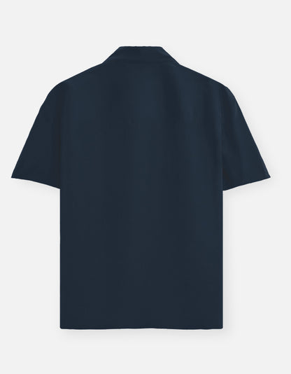 Color_NavyBlue. Premium unisex oversized button-down shirt with a wide, boxy fit and dropped shoulders. Made from breathable solid-colored cotton. Features a structured collar and longline hem, perfect for layered streetwear or minimalist smart-casual outfits.
