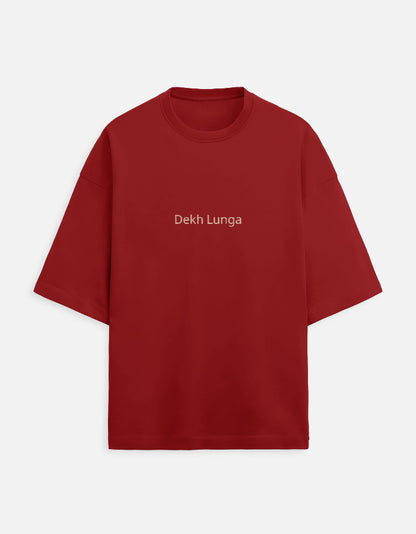 Deep maroon oversized unisex t-shirt with a dual-sided graphic. The front features the Hindi text "Dekh Lunga" (I will handle it) in light gray. The back features the Hindi text "मत देख" (Mat Dekh - Don't look) in light gold, positioned on the upper center. Boxy fit, typographic statement apparel.