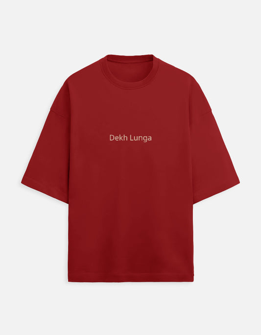 Deep maroon oversized unisex t-shirt with a dual-sided graphic. The front features the Hindi text "Dekh Lunga" (I will handle it) in light gray. The back features the Hindi text "मत देख" (Mat Dekh - Don't look) in light gold, positioned on the upper center. Boxy fit, typographic statement apparel.