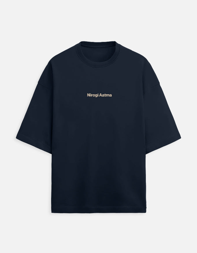 Navy Blue oversized unisex t-shirt featuring a centered, small graphic of the text "Nirogi Aatma" (Healthy Soul) written in light brown or gold lettering. Soft cotton, drop-shoulder, boxy casual apparel with a spiritual or motivational typographic design.