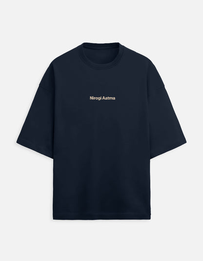 Navy Blue oversized unisex t-shirt featuring a centered, small graphic of the text "Nirogi Aatma" (Healthy Soul) written in light brown or gold lettering. Soft cotton, drop-shoulder, boxy casual apparel with a spiritual or motivational typographic design.
