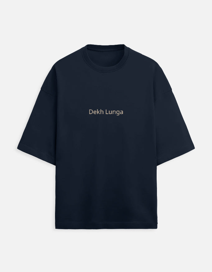 Navy Blue oversized unisex t-shirt with a dual-sided graphic. The front features the Hindi text "Dekh Lunga" (I will handle it) in light gray. The back features the Hindi text "मत देख" (Mat Dekh - Don't look) in light gold, positioned on the upper center. Boxy fit, typographic statement apparel.