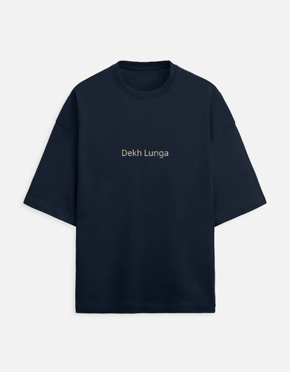 Navy Blue oversized unisex t-shirt with a dual-sided graphic. The front features the Hindi text "Dekh Lunga" (I will handle it) in light gray. The back features the Hindi text "मत देख" (Mat Dekh - Don't look) in light gold, positioned on the upper center. Boxy fit, typographic statement apparel.