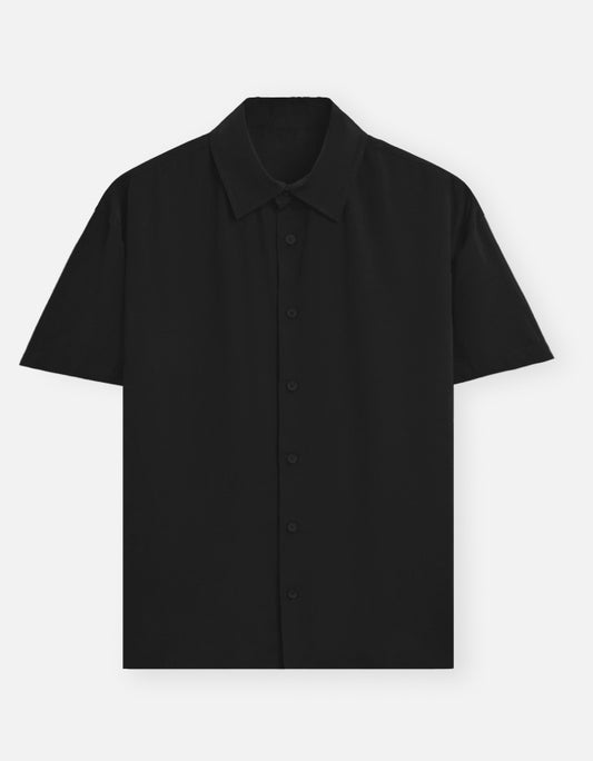 Color_Black. Classic long-sleeved button-down shirt in a solid premium cotton fabric. Features a structured collar, adjustable cuffs, and a regular fit designed for a versatile unisex silhouette. Ideal for smart-casual styling and layering.