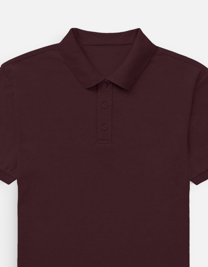 Color_Maroon. Classic short-sleeved polo shirt with a structured ribbed collar and two-button placket. High-quality pique cotton fabric in a solid color, offering a sharp yet relaxed regular fit for a unisex smart-casual aesthetic.