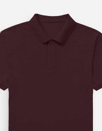 Color_Maroon. Classic short-sleeved polo shirt with a structured ribbed collar and two-button placket. High-quality pique cotton fabric in a solid color, offering a sharp yet relaxed regular fit for a unisex smart-casual aesthetic.