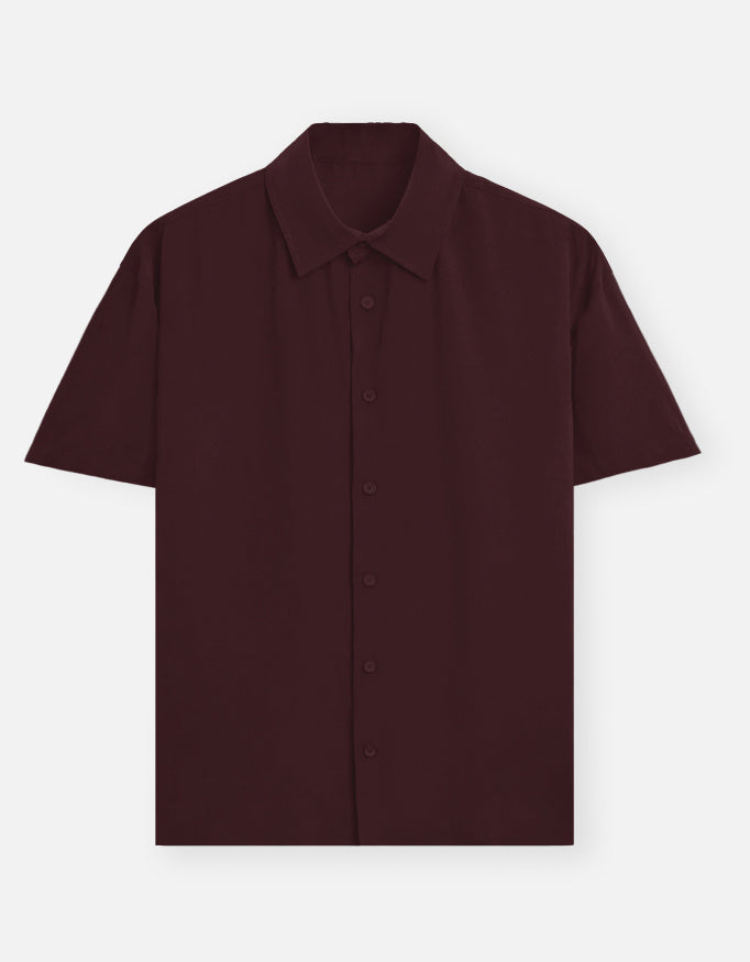 Color_Maroon. Premium unisex oversized button-down shirt with a wide, boxy fit and dropped shoulders. Made from breathable solid-colored cotton. Features a structured collar and longline hem, perfect for layered streetwear or minimalist smart-casual outfits.