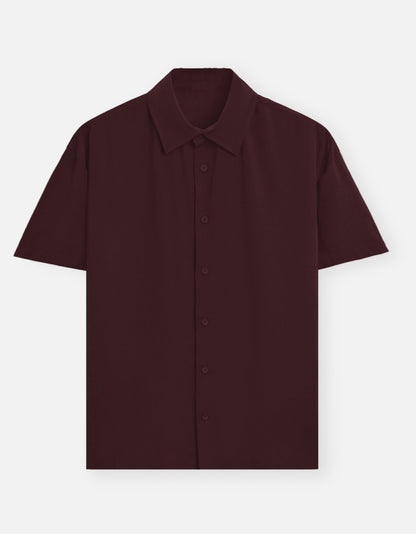 Color_Maroon. Premium unisex oversized button-down shirt with a wide, boxy fit and dropped shoulders. Made from breathable solid-colored cotton. Features a structured collar and longline hem, perfect for layered streetwear or minimalist smart-casual outfits.