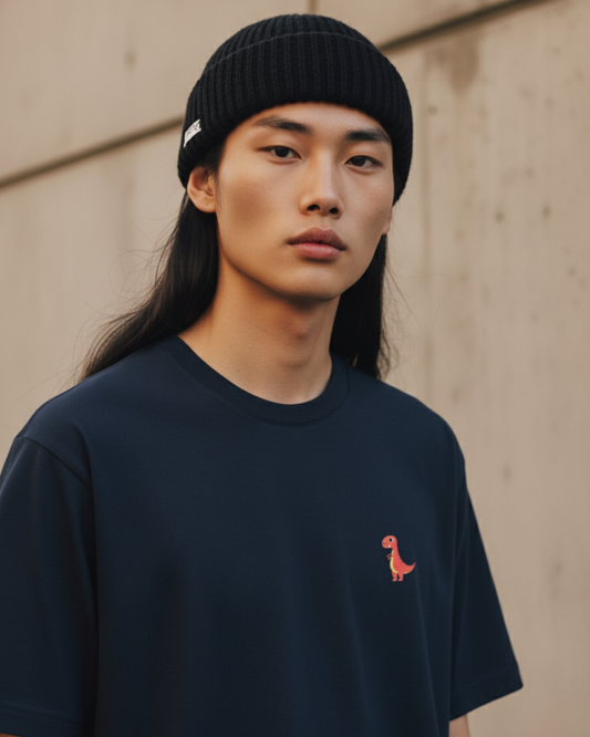 Oversized deep navy streetwear t-shirt with a small orange dinosaur embroidery on the chest. Features dropped shoulders, heavyweight cotton fabric, and a boxy fit.